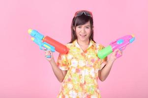 uma linda mulher asiática mostra um gesto enquanto segura uma pistola de água de plástico durante o festival songkran foto