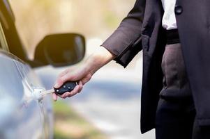 fechadura de porta aberta de mulher de negócios com chave e controle remoto eletrônico foto