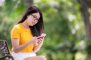linda mulher asiática deitada no jardim e usando um telefone celular, pode pesquisar informações ou fazer compras online na internet foto