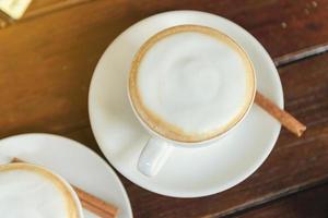 vista superior da xícara de cappuccino de café quente com espuma de leite na mesa de madeira foto