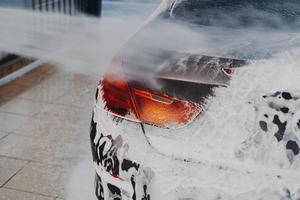 lavando a superfície externa do carro com lavadora de alta pressão na estação de limpeza self-service ao ar livre foto