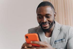 atraente jovem autônomo afro-americano confiante conversando com parceiros no smartphone