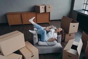 jovem espanhola muito feliz comprou um novo apartamento. senhora está relaxando na poltrona. foto