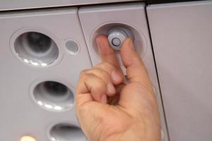 mão para ajustar o painel do console. o ar condicionado, leve, assento de avião de baixo custo. enquanto a bordo de uma aeronave, foco seletivo. desfocar o estilo vintage de cor de fundo. foto