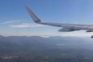 asa de avião com belo horizonte do nascer do sol. avião voando no céu azul. vista da janela do avião. voo comercial da companhia aérea pela manhã com luz solar. asa de avião acima das nuvens. foto