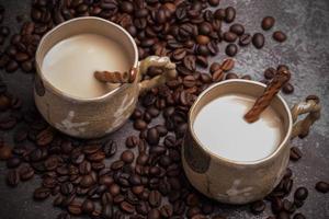 duas canecas de café com grãos de café em um pano de fundo escuro. foto