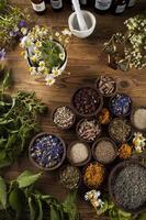medicina alternativa, ervas secas e argamassa no fundo da mesa de madeira foto