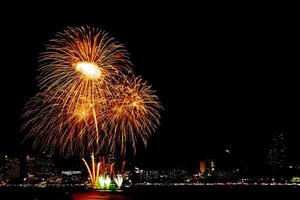 muitos fogos de artifício piscando com fundo de paisagem urbana à noite celebram o ano novo. foto
