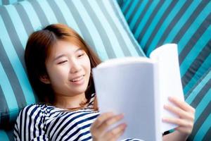 linda de retrato jovem asiática relaxe mentindo lendo livro no sofá no quarto em casa, menina estudo literatura, educação e conceito de estilo de vida. foto