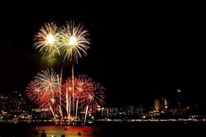 muitos fogos de artifício piscando com fundo de paisagem urbana à noite celebram o ano novo. foto