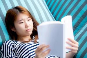 linda de retrato jovem asiática relaxe mentindo lendo livro no sofá no quarto em casa, menina estudo literatura, educação e conceito de estilo de vida. foto
