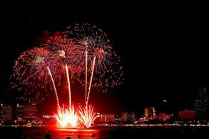 muitos fogos de artifício piscando com fundo de paisagem urbana à noite celebram o ano novo. foto