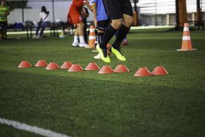 táticas de bola de futebol no campo de grama com barreira para treinar habilidades de salto de crianças foto