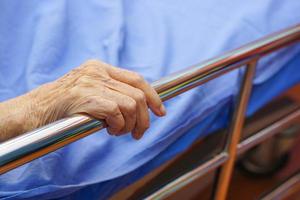 as mãos de uma paciente idosa ou idosa como agarrar na beira da cama. cuidados de saúde e conceito médico. foto