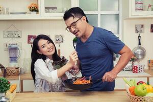 casal feliz comendo vegetais. se divertindo na cozinha. foto