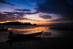 lindo céu e pôr do sol na praia com silhueta de barco de pesca. foto