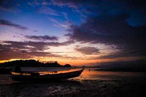 lindo céu e pôr do sol na praia com silhueta de barco de pesca. foto