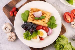 café da manhã consiste em pão, ovos cozidos, molho de salada de uva preta, tomate. foto