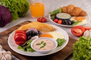 café da manhã consiste em pão, ovo frito, molho de salada, uvas pretas, tomates. foto