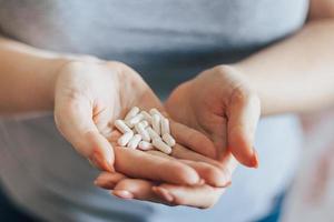 a mão da mulher está segurando pílulas. overdose de cápsulas medicinais em close-up de palmas. dia mundial da saúde. foto
