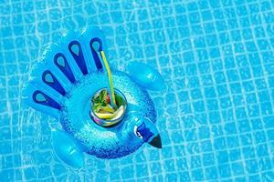 fresco coctail mojito no brinquedo de pavão azul inflável na piscina. conceito de férias. foto