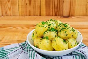 batatas jovens em fundo de madeira foto