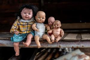 um grupo de bonecas sentado em uma velha casa de madeira.