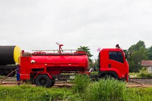 um caminhão de bombeiros vermelho está esperando perto dos trilhos da ferrovia. foto