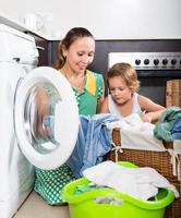 mulher com criança perto da máquina de lavar roupa