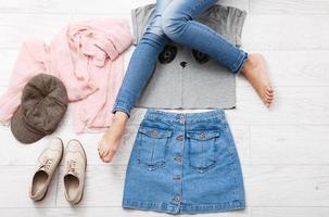 roupa casual de verão com diferentes acessórios e pernas femininas em jeans no piso de madeira branco. vista superior e copie o espaço. foto