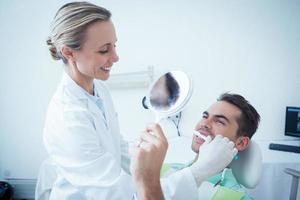 dentista feminina escovar os dentes do homem foto