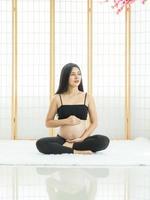 uma linda mulher grávida sentada na sala japonesa para pegar seu estômago foto