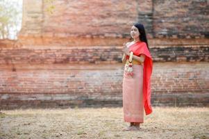 mulheres tailandesas atraentes em vestido tradicional tailandês seguram guirlandas de flores frescas para entrar em um templo baseado na tradição do festival songkran na tailândia foto