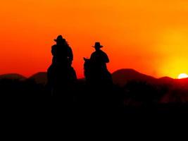 o vaqueiro ocidental forçou seus cavalos a parar enquanto o sol estava se pondo, em terras onde a lei ainda não chegou