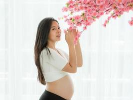 mulher bonita grávida fica segurando flores em uma sala de estilo japonês foto