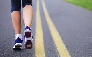 pés femininos de corredor correndo na estrada