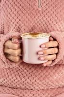mãos segurando uma xícara de chocolate, jaqueta aconchegante rosa, linda