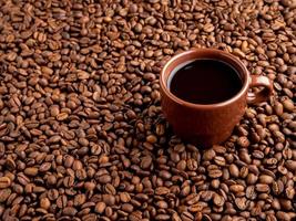xícara marrom de café expresso no fundo de grãos de café espalhados, vista lateral, copie o espaço foto