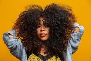 retrato da beleza da mulher afro-americana com penteado afro e maquiagem glamour. mulher brasileira. mestiço. cabelo encaracolado. Penteado. fundo amarelo. foto