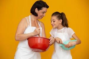 conceito de dia das mães. filha e mãe preparando uma receita em fundo amarelo foto