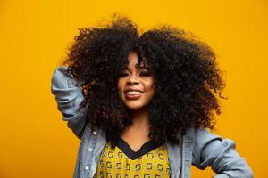 retrato da beleza da mulher afro-americana com penteado afro e maquiagem glamour. mulher brasileira. mestiço. cabelo encaracolado. Penteado. fundo amarelo. foto