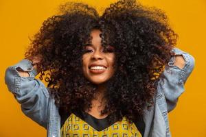 retrato da beleza da mulher afro-americana com penteado afro e maquiagem glamour. mulher brasileira. mestiço. cabelo encaracolado. Penteado. fundo amarelo. foto