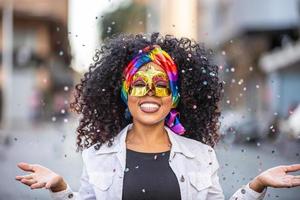 festa carnavalesca. mulher brasileira de cabelo encaracolado fantasiada soprando confete