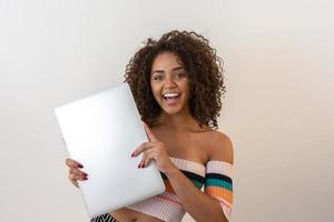 retrato de uma jovem afro-americana sorridente segurando o laptop sobre fundo branco foto