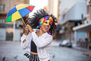 mulher jovem de cabelos cacheados comemorando a festa de carnaval brasileira com guarda-chuva de frevo na rua. foto