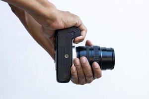 close-up isolado das mãos e dedos de um homem tailandês segurando uma câmera de filme dslr preta velha. foto