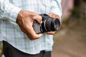 close-up vista da mão do idoso segurando uma câmera de filme antigo. foto