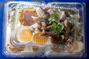 close-up vista superior de arroz de perna de porco em uma caixa de plástico transparente. foto