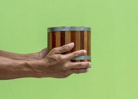 balde de madeira antigo, carregando a mão com parede verde. foto