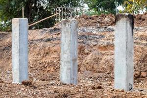 muitos postes de concreto no solo escavado para construção. foto